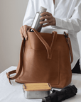 Leather Tote Bag
Full grain leather, unlined hand bag. It features two open exterior pockets and one internal zippered pocket. It comes with fixed leather handles. It’s held shut by a sturdy snap closure.