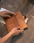 Natural-grained unlined wallet. It features a front snap closure, 8 card slots, 2 bill compartments plus a zippered interior pocket.