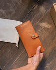 Natural-grained unlined wallet. It features a front snap closure, 8 card slots, 2 bill compartments plus a zippered interior pocket.