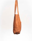 Leather Tote Bag
Full grain leather, unlined hand bag. It features two open exterior pockets and one internal zippered pocket. It comes with fixed leather handles. It’s held shut by a sturdy snap closure.