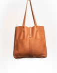 Leather Tote Bag
Full grain leather, unlined hand bag. It features two open exterior pockets and one internal zippered pocket. It comes with fixed leather handles. It’s held shut by a sturdy snap closure.