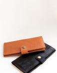 Natural-grained unlined wallet. It features a front snap closure, 8 card slots, 2 bill compartments plus a zippered interior pocket.