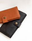 Natural-grained unlined wallet. It features a front snap closure, 8 card slots, 2 bill compartments plus a zippered interior pocket.