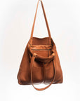 Leather Tote Bag, unlined hand bag. It features two open exterior pockets and one internal zippered pocket. It comes with fixed leather handles. It’s held shut by a sturdy snap closure.
