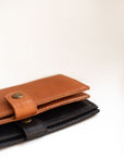 Natural-grained unlined wallet. It features a front snap closure, 8 card slots, 2 bill compartments plus a zippered interior pocket.