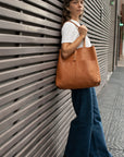 Leather unlined hand bag. It features two open exterior pockets and one internal zippered pocket. It comes with fixed leather handles. It’s held shut by a sturdy snap closure.