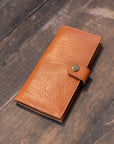 Natural-grained unlined wallet. It features a front snap closure, 8 card slots, 2 bill compartments plus a zippered interior pocket.