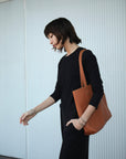 Leather Tote Bag unlined hand bag. It features two open exterior pockets and one internal zippered pocket.