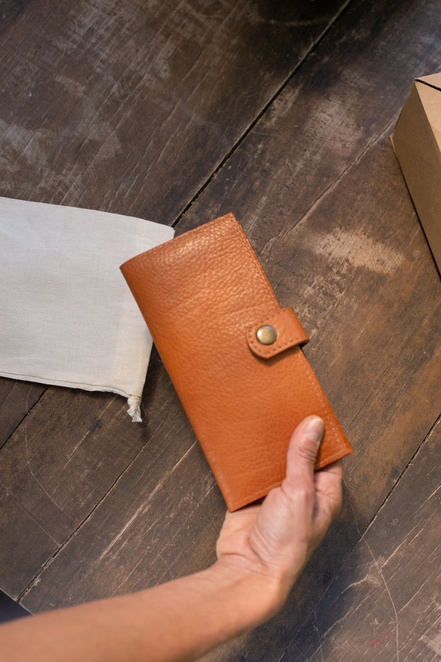 Natural-grained unlined wallet. It features a front snap closure, 8 card slots, 2 bill compartments plus a zippered interior pocket.