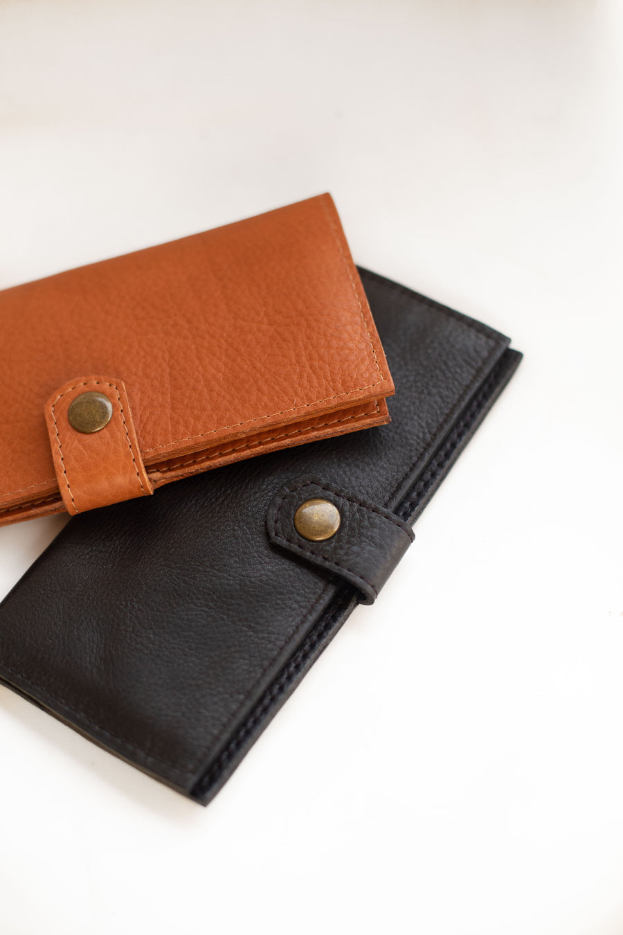 Natural-grained unlined wallet. It features a front snap closure, 8 card slots, 2 bill compartments plus a zippered interior pocket.