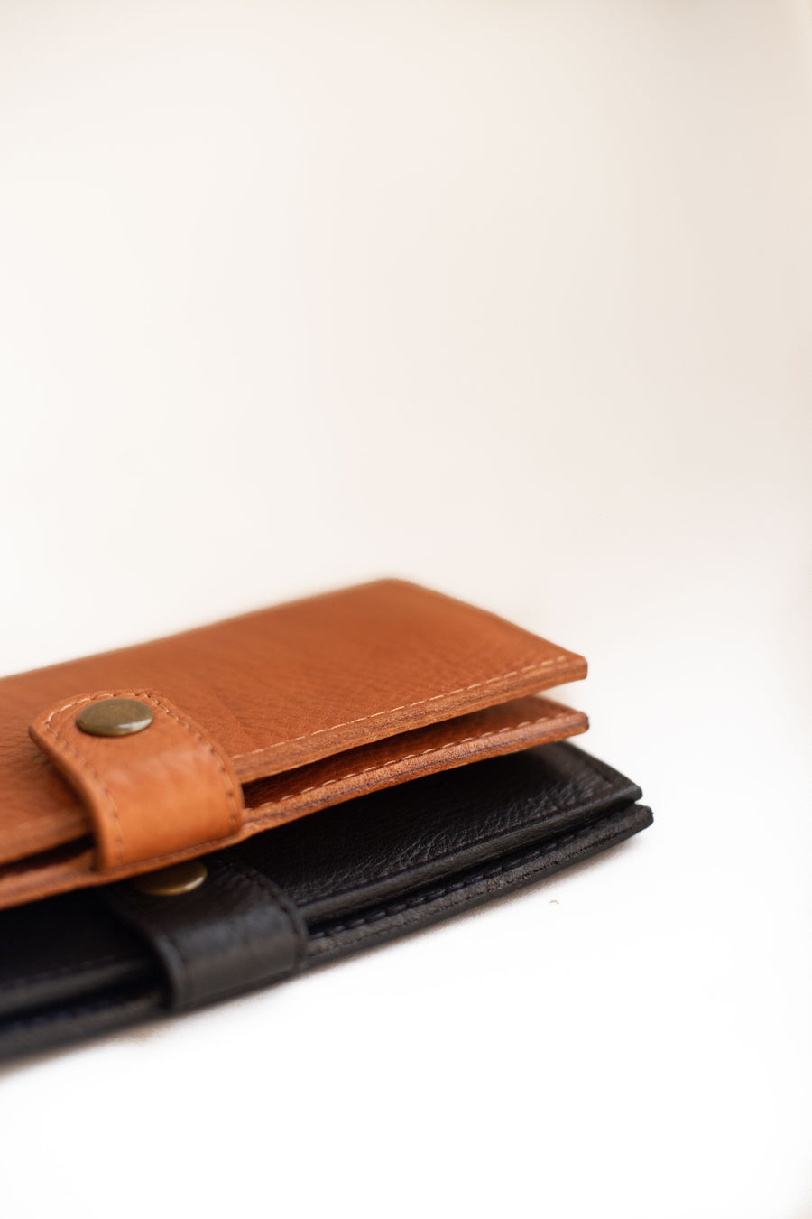 Natural-grained unlined wallet. It features a front snap closure, 8 card slots, 2 bill compartments plus a zippered interior pocket.